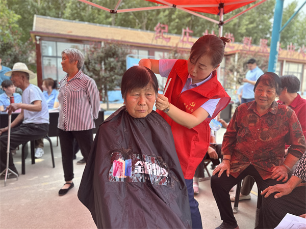 理发师志愿者贴心地为村民戴好围布,一边唠着家常,一边询问喜欢的发型